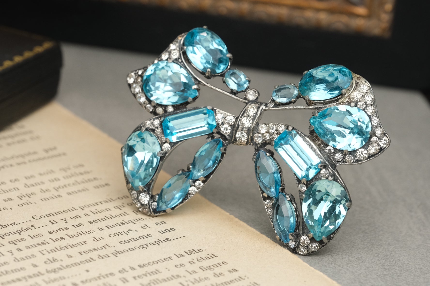 Angled view of Eisenberg Original aqua blue glass bow brooch