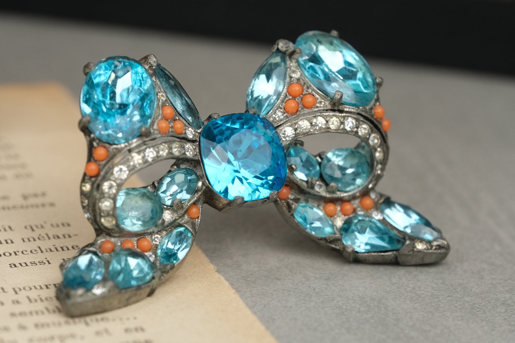 Eisenberg Original bow brooch with vivid blue stones and coral-color bead accents