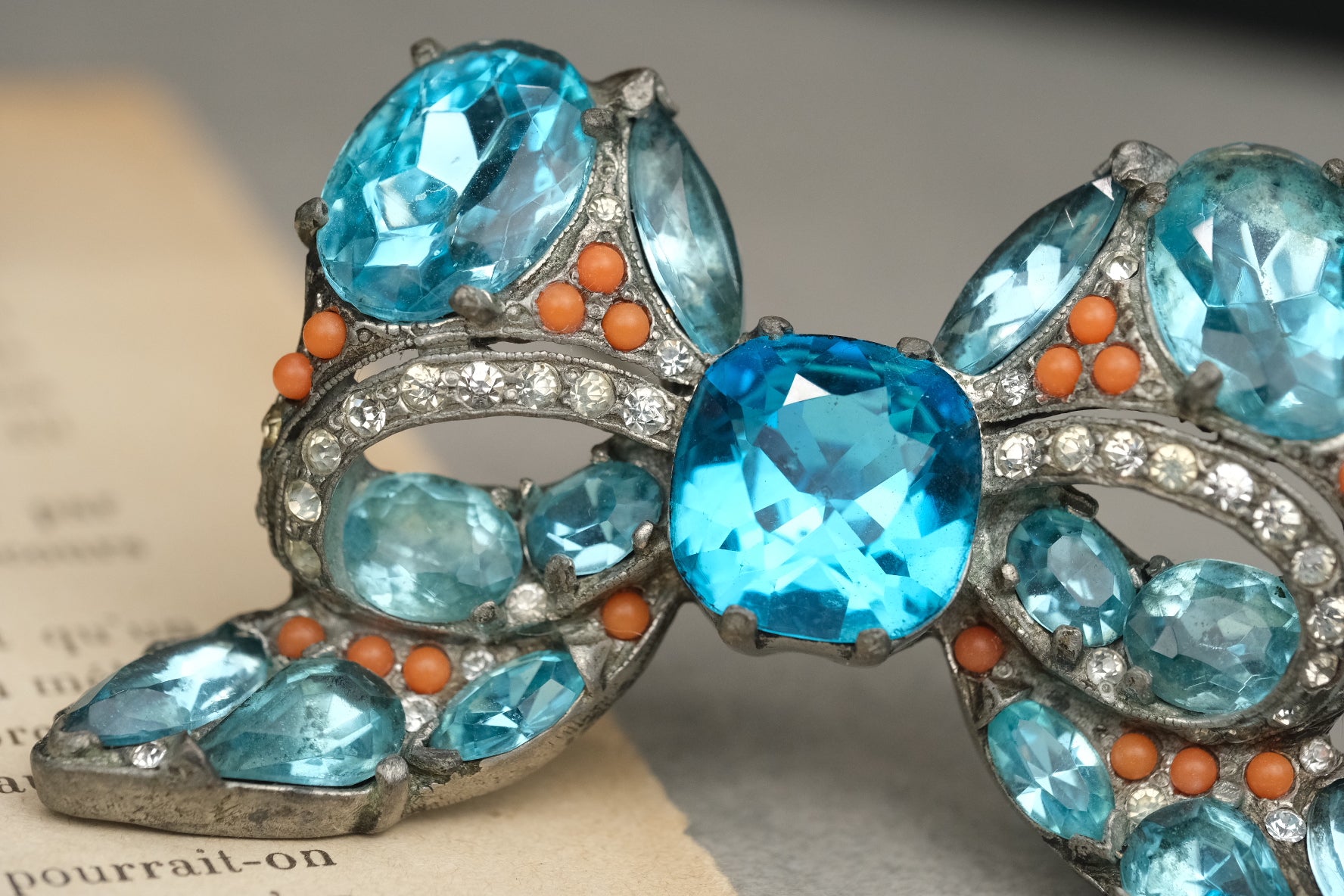 Close-up of blue stones, coral-color beads, and rhinestones on Eisenberg Original bow brooch