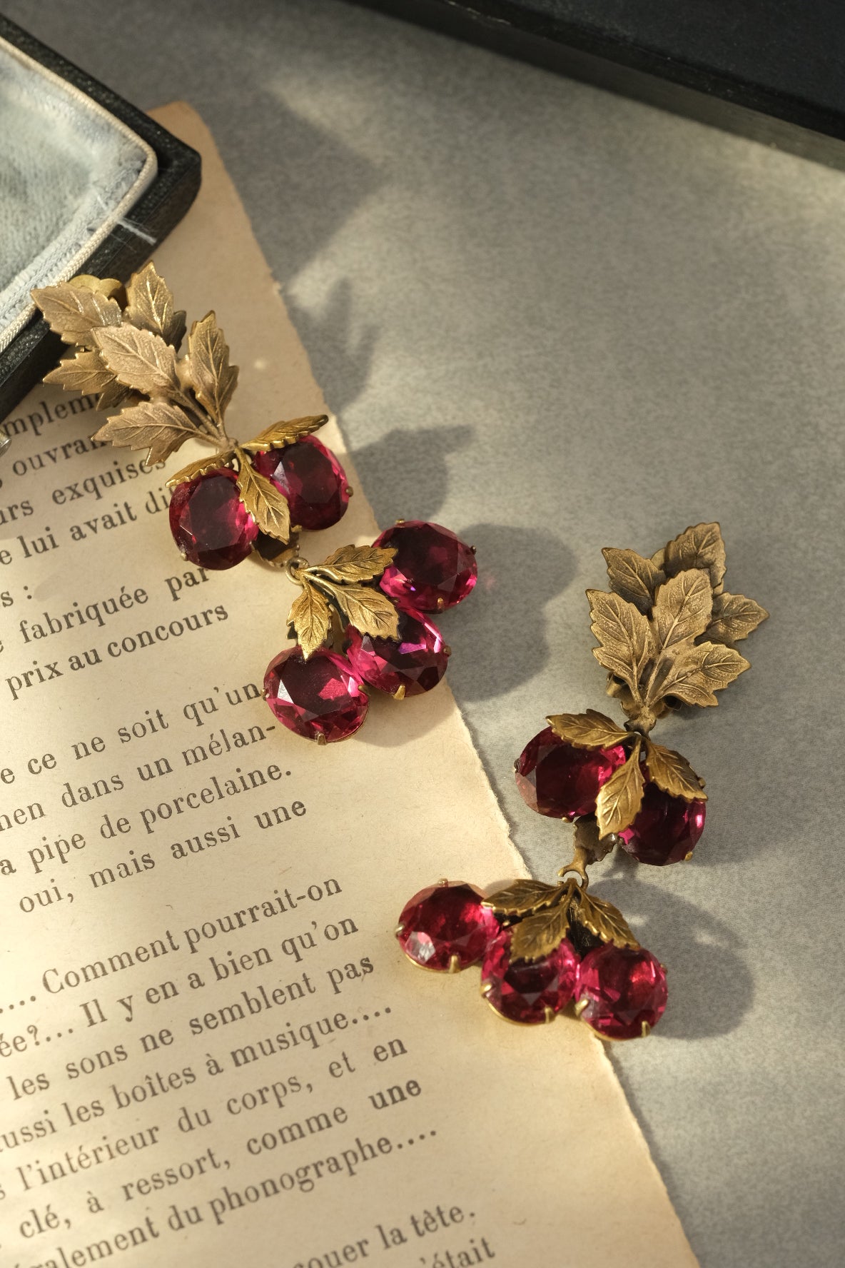 Vintage ruby glass fruit and gold-tone leaf clip-on earrings in natural light