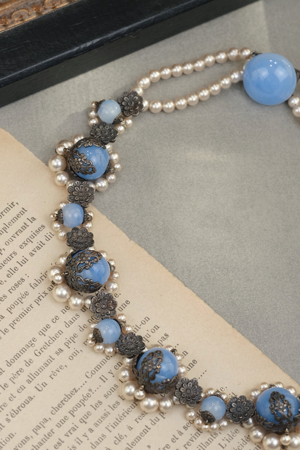Blue glass bead necklace with lace-like metal flower plaques detail