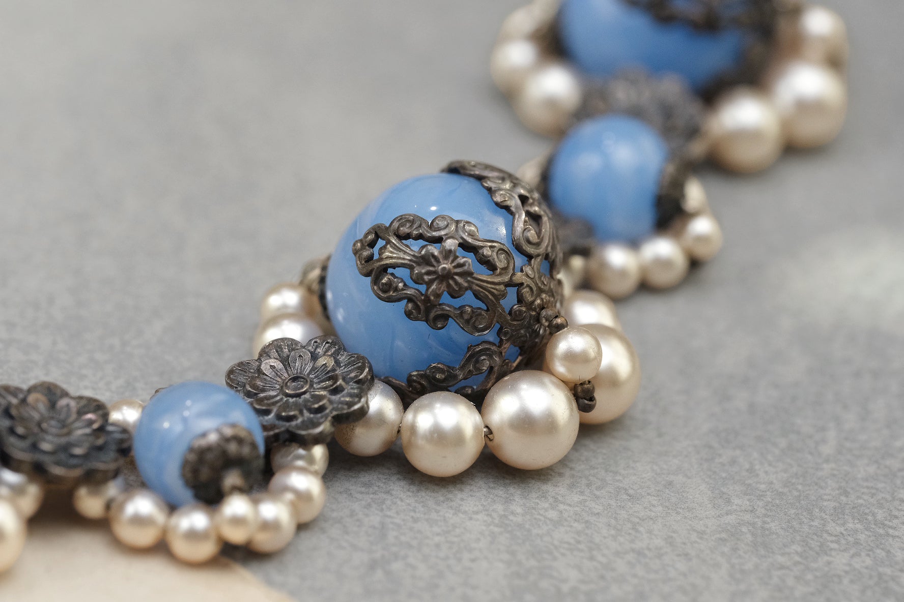 Large blue glass bead with openwork metal filigree cap close-up