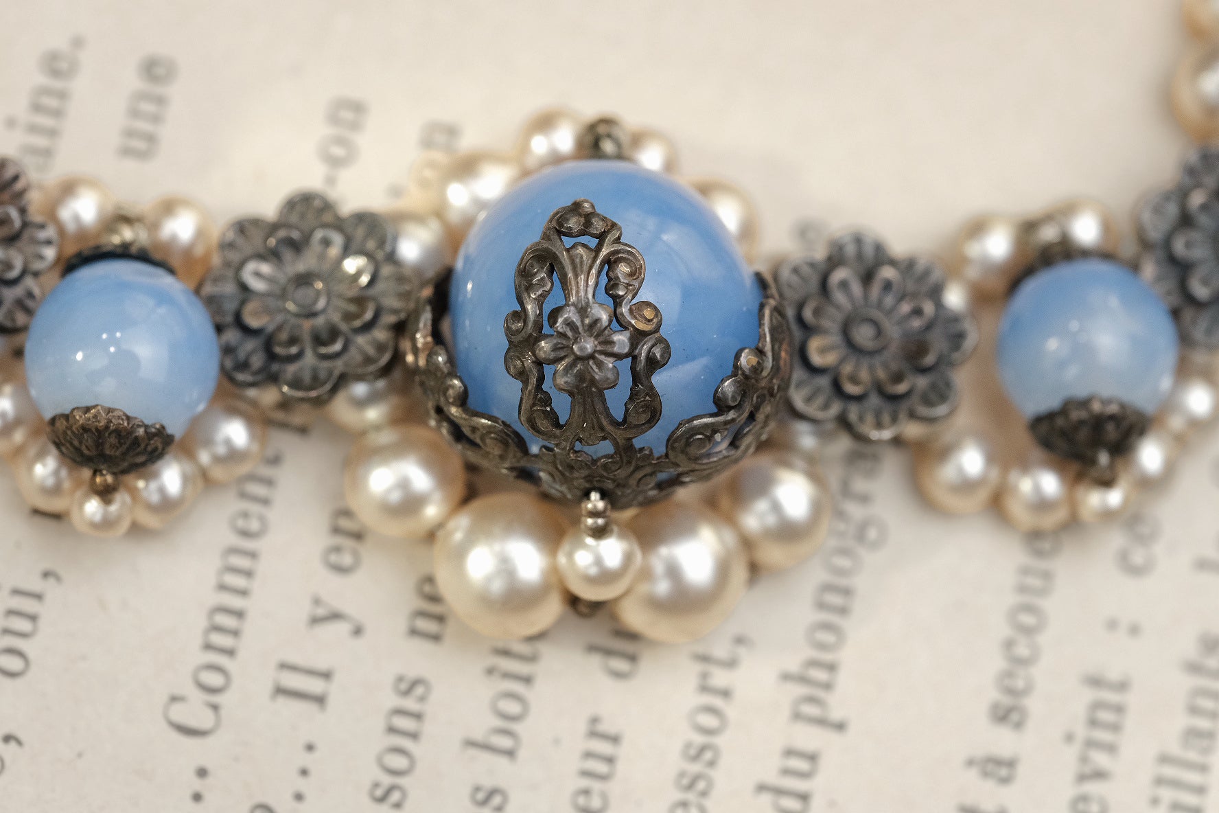 Ornate blue glass bead with lace-like metal floral setting