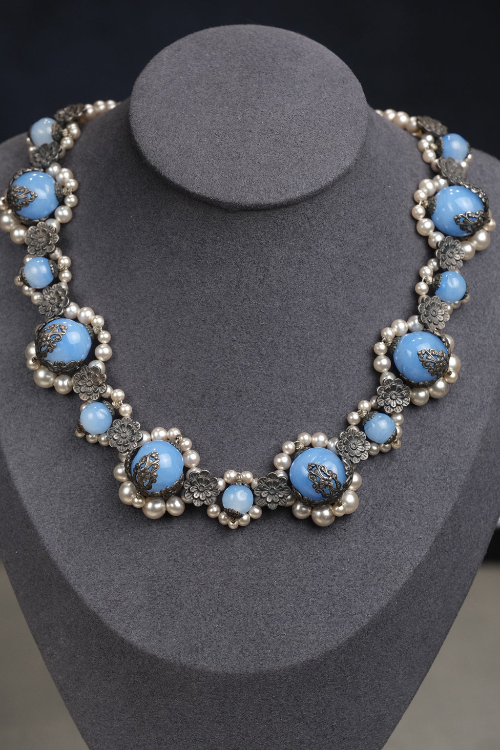 Blue glass and pearl necklace displayed on bust