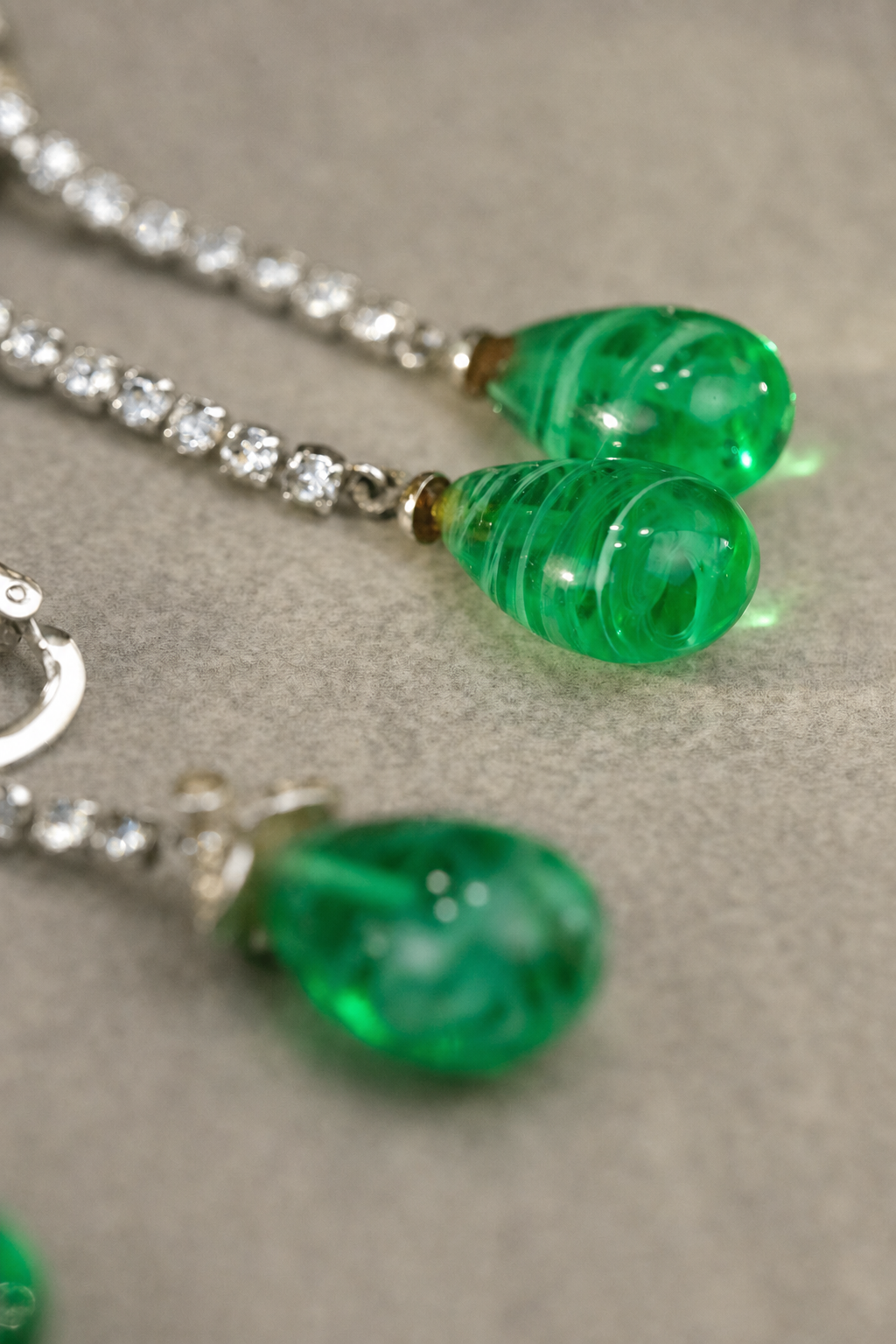 Close-up of translucent green swirled glass teardrop beads and rhinestone drops