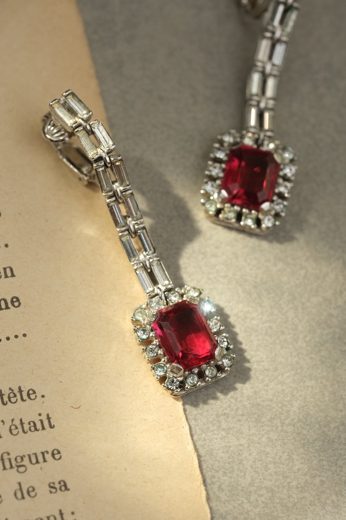 Close-up of emerald-cut red glass stone and clear rhinestone halo on vintage Ciner earrings