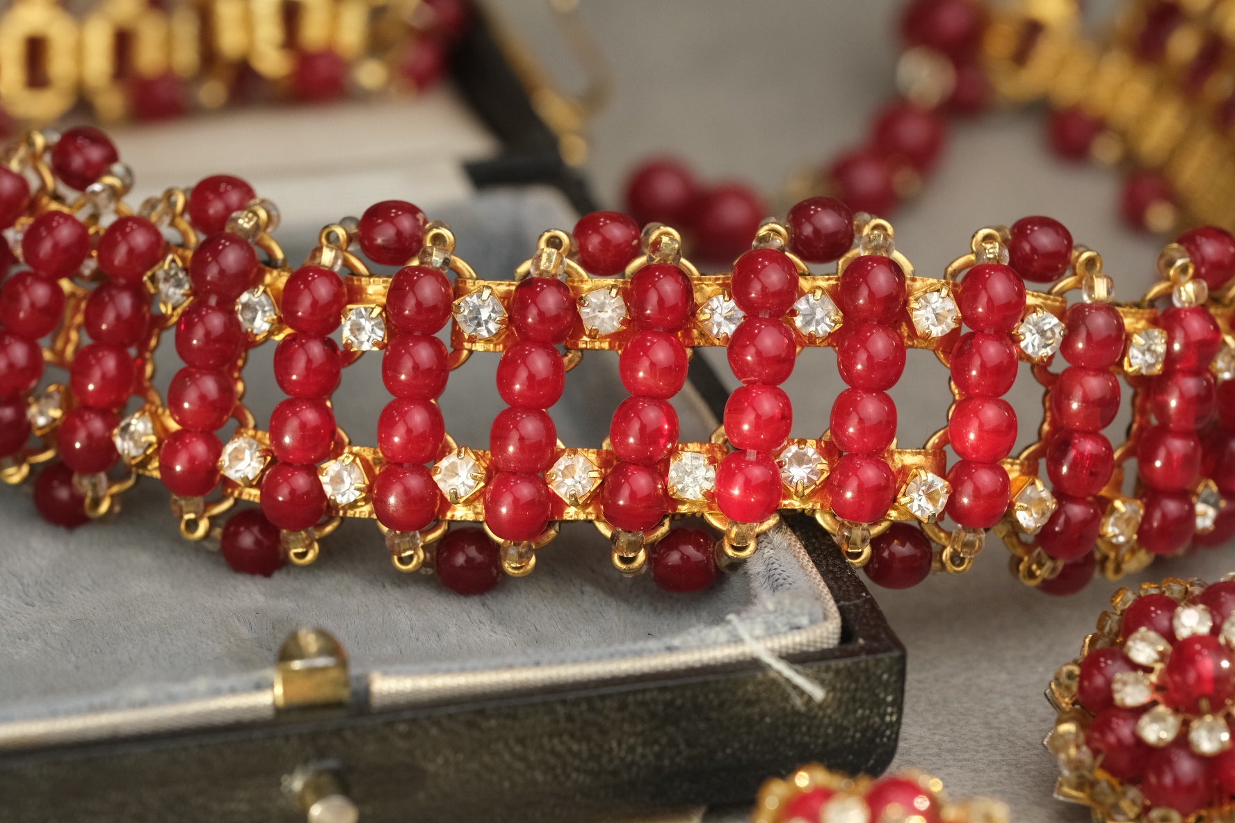 Close-up of red glass bead rows and clear rhinestones on gold-tone necklace